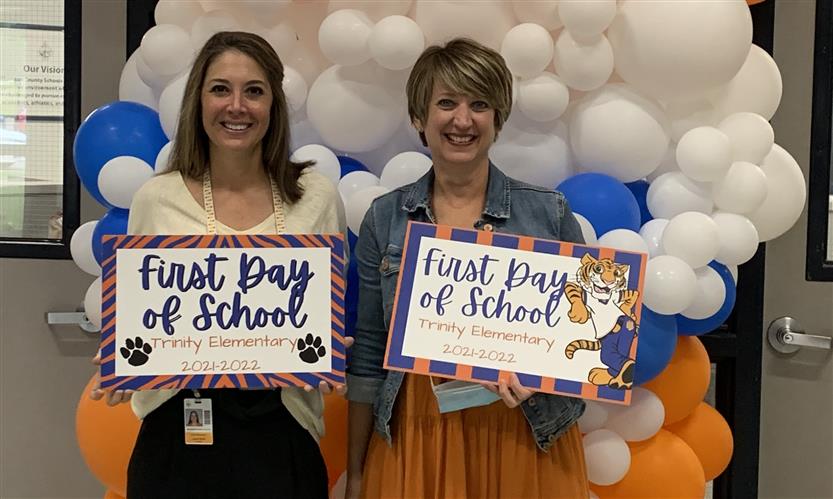 Two administrators hold up First Day signs
